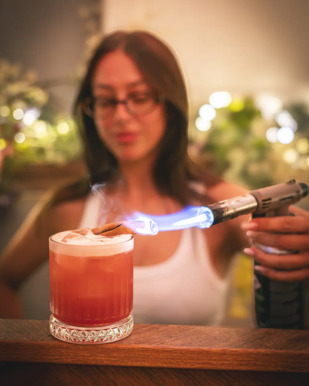 Bartender van WonderBar Genk brandt met een gasbrander het kaneelstokje af op een sour, blauwe vlam boven het glas