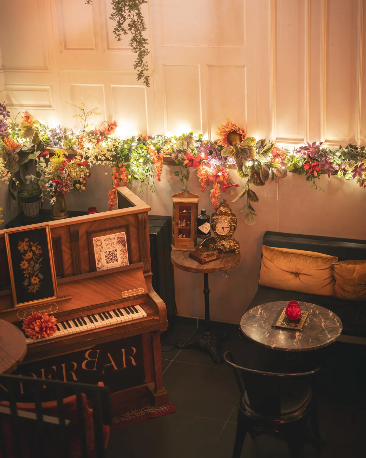 Ruimer zicht op de pianohoek met bloemenrand langs de wand in WonderBar Genk