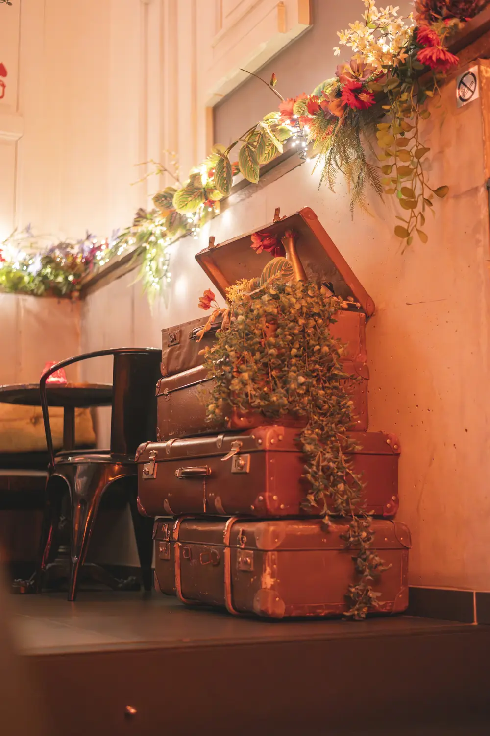 Stapel vintage koffers met klimplant en bloemenslinger met lampjes in WonderBar Genk