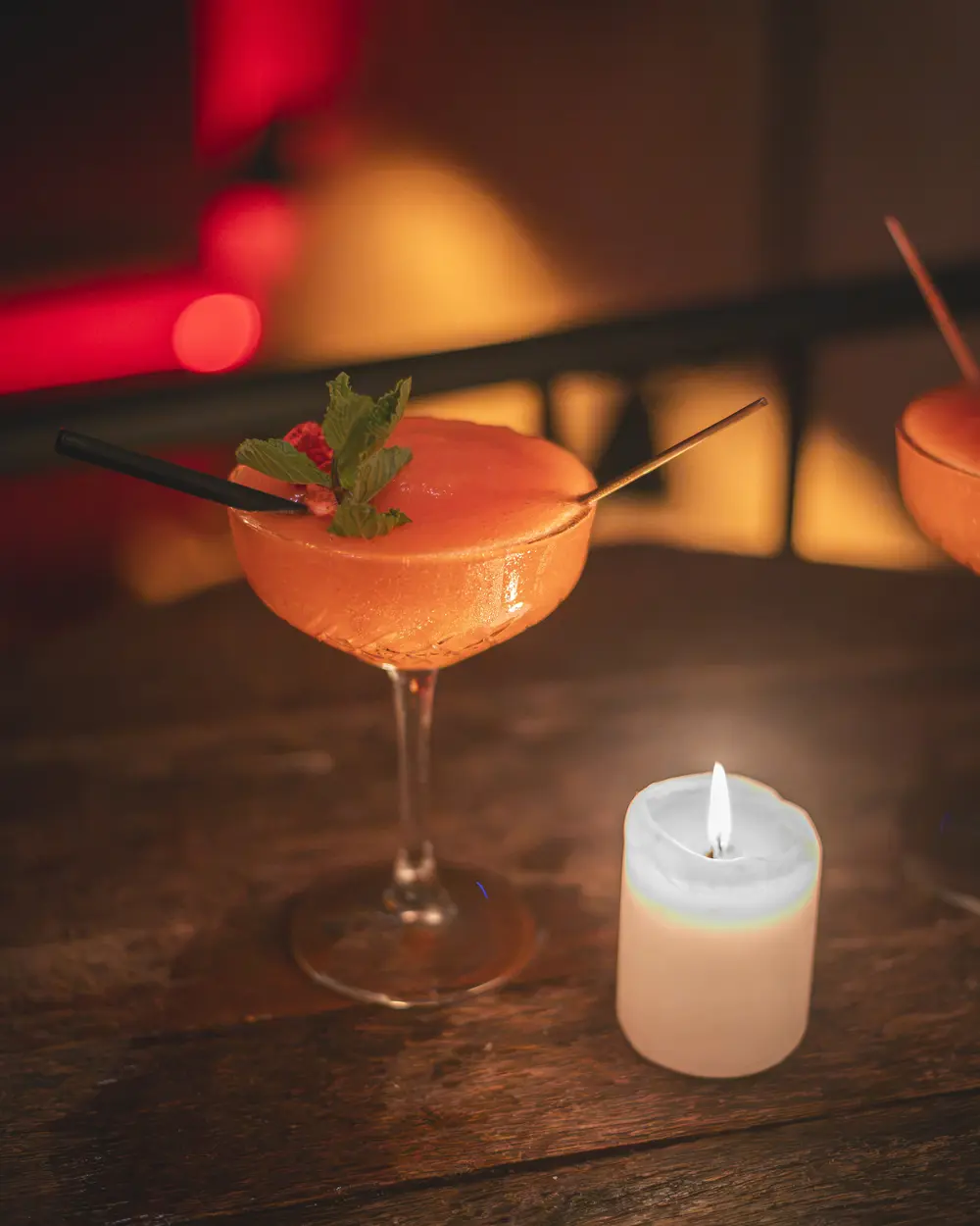 Frozen Strawberry Daiquiri in coupe met munt en aardbei naast een kaars op de houten tafel in WonderBar Genk