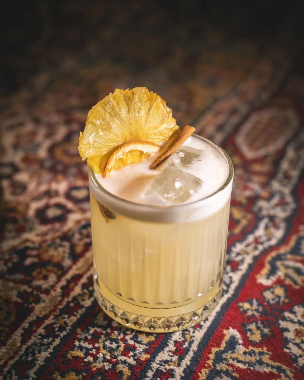 The Golden Hour Sour met gedroogde ananas en kaneel op het oosterse tapijt van WonderBar Genk