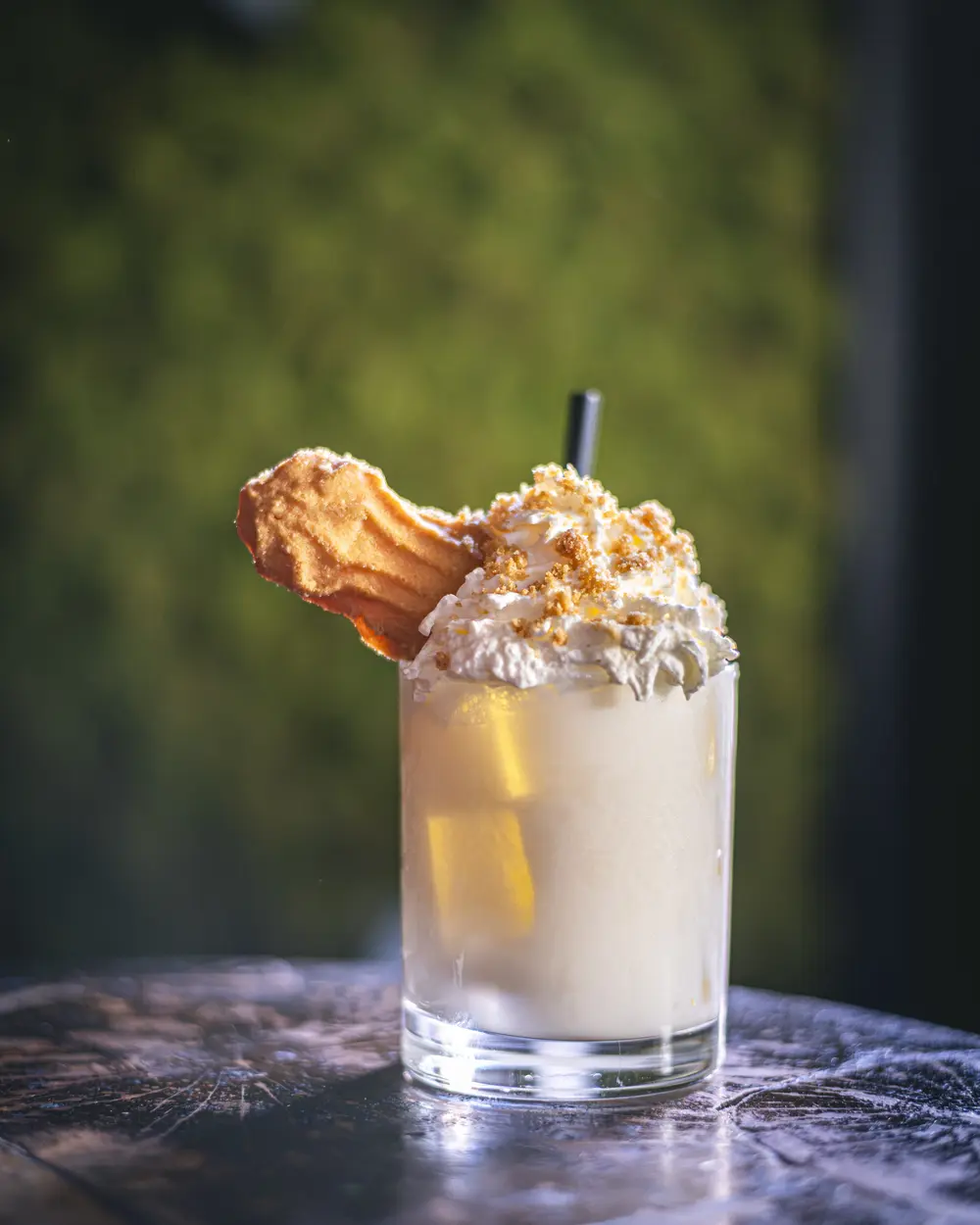 Key Lime Pie-cocktail met slagroom, koekje en crumble in tumbler op de marmeren tafel van WonderBar Genk