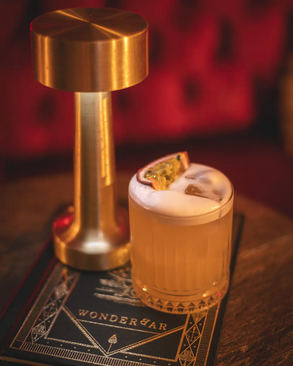 Port Light met passievrucht en schuimlaag op het WonderBar-menuboek met gespiegelde B, naast een koperen tafellamp